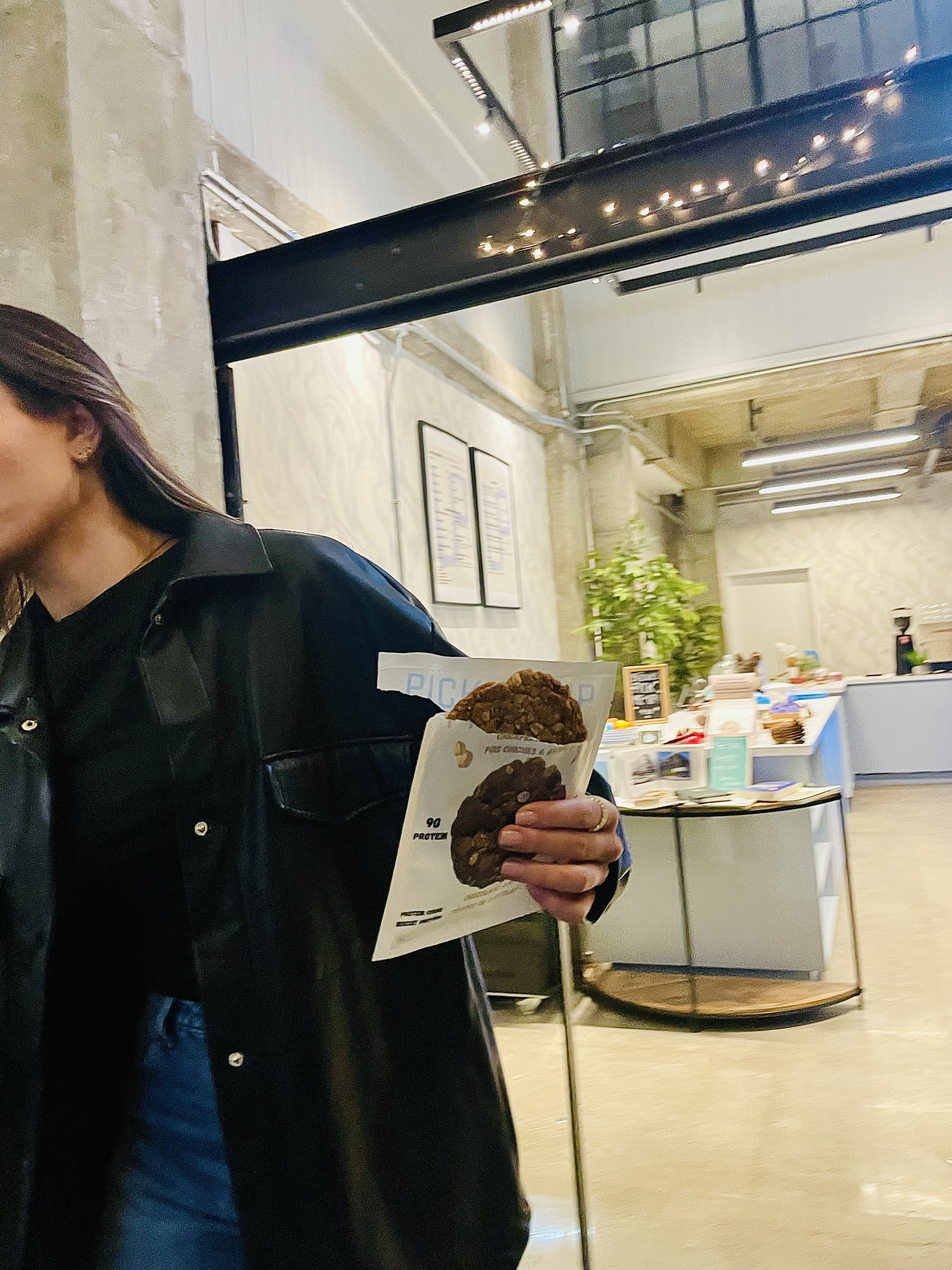 Person holding a Pick Me Up cookie in a café setting